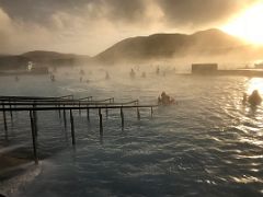 02C Steam rises from the hot blue refreshing water highlighted by the low sun at the Blue Lagoon geothermal spa Iceland