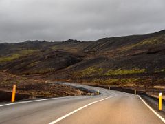 01D Road 42 snakes past a green moss covered lava hill as it nears Kleifarvatn lake on Reykjanes Peninsula Iceland