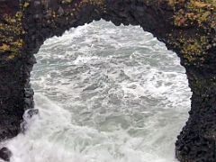 04B The sea pounds the Gatklettur (Hellnar Arch) naturally formed stone arch opening in Arnarstapi Snaefellsnes Peninsula Iceland