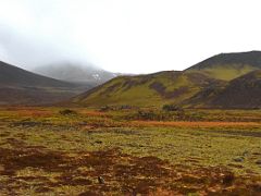 02C Driving on road 558 with red soil, green moss covered black lava, and a red and green crater in Berserkjahraun lava field Snaefellsnes Peninsula Iceland