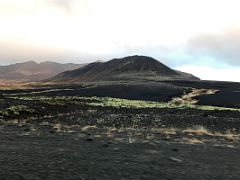 06A Black lava soil and green moss leads to a black crater in Berserkjahraun lava field Snaefellsnes Peninsula Iceland