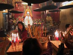 16A People offering incense sticks and candles with statues behind at Lit Shing Kung, part of Man Mo Temple Hong Kong