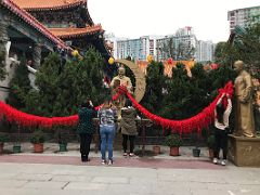 12 A woman knots a red rope in the hope of prosperity in love between the statue of Yue Lao, the god of marriage, and the spouse at Wong Tai Sin temple Hong Kong