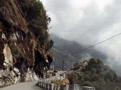 03B The Wide Fast Road Contoured Around The Hill Passing Prayer Flags And A Buddhist Shrine As It Climbed On The Drive From Gangtok To Tsomgo Lake Sikkim India