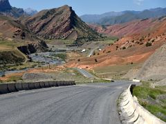 08C The Pamir Highway snakes past a river and green fertile land and red hills between Chirchik Pass and Taldyk Pass on the way to Lenin Peak Base Camp