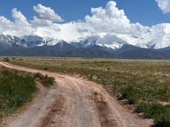 16B Driving on the dirt road across the plain with Lenin Peak towering in the distance on the way to Lenin Peak Base Camp