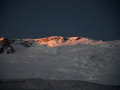 05B The first rays of sunrise shine the Lenin Peak summit ridge orange after leaving crampon point on the way to Ak-Sai Travel Lenin Peak Camp 2 5400m