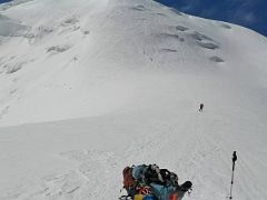 03A Having a rest snack break on the ridge with the steep face of Razdelnaya Peak beyond on the way to Ak-Sai Travel Lenin Peak Camp 3 6100m