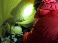 07B Lal Sing Tamang finishes breakfast and gets dressed for the cold and wind before leaving for the summit from our tent at Lenin Peak camp 4 6430m