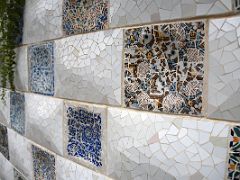 12A The wall next to the entrance stairs is covered with trencadis mosaic made of tile shards Park Guell Barcelona Spain