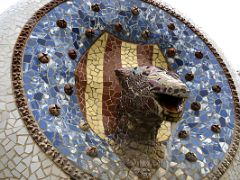 14A Catalan coat of arms with a snake trencadis mosaic fountain on the entrance steps Park Guell Barcelona Spain