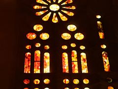 21C The afternoon sun shines through the west stained glass windows with oranges and yellows Sagrada Familia Barcelona Spain