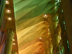 21D The afternoon sun shines thru the stained glass windows on the west side with greens, reds, oranges and yellows illuminated on the ceiling Sagrada Familia Barcelona Spain