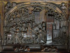 04B The stalls in the lower tier feature historical reliefs of scenes from the conquest of Granada Choir Toledo Cathedral Spain