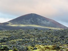 06B Green moss covered lava leads to a black and reddish crater in Berserkjahraun lava field Snaefellsnes Peninsula Iceland