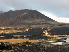 08A Green moss covered lava leads to a small stream and up to a black, green and reddish crater in Berserkjahraun lava field Snaefellsnes Peninsula Iceland