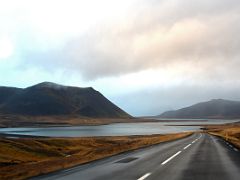 02B Road 54 snakes toward a causeway on Seljafjordur inlet with Kolgrafamuli mountain to left and Klakkur mountain to right driving to Grundarfjordur Snaefellsnes Peninsula Iceland