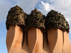 05A A three-stack chimney is topped with broken bottle glass shards Roof La Pedrera Casa Mila Gaudi Barcelona Spain